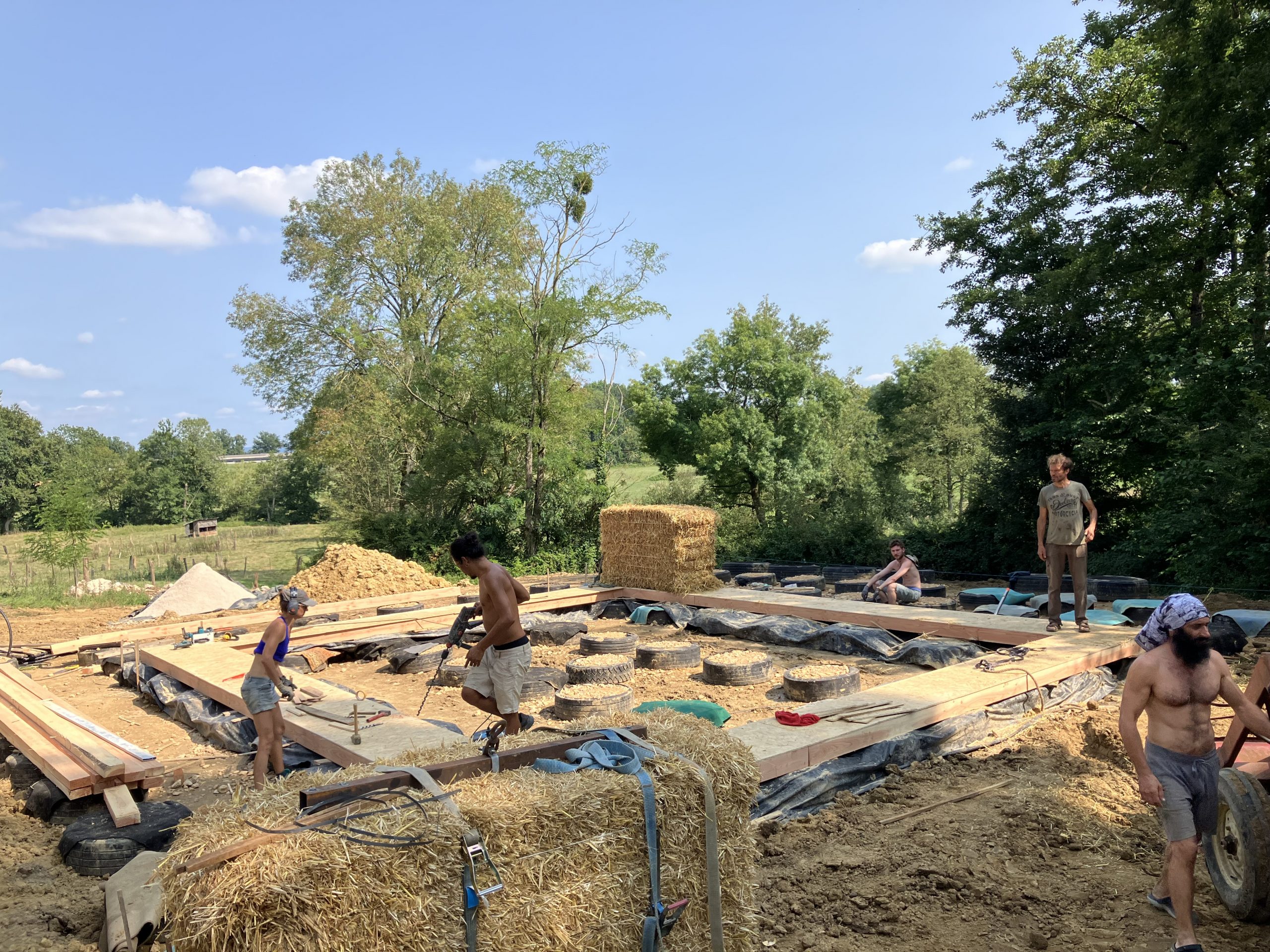 Chantier participatif de paille porteuse en plein champ, murs en gros ballots