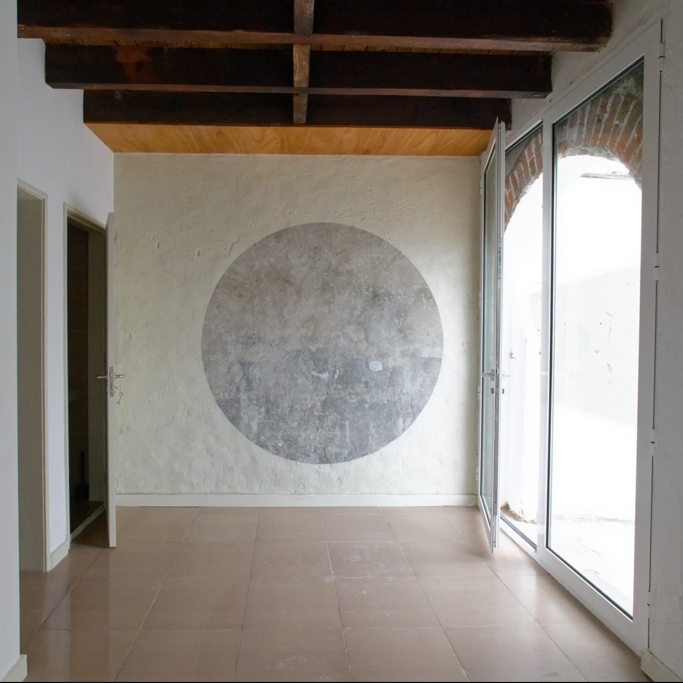 Entrée rénovée, médaillon gris au mur et porte vitrée