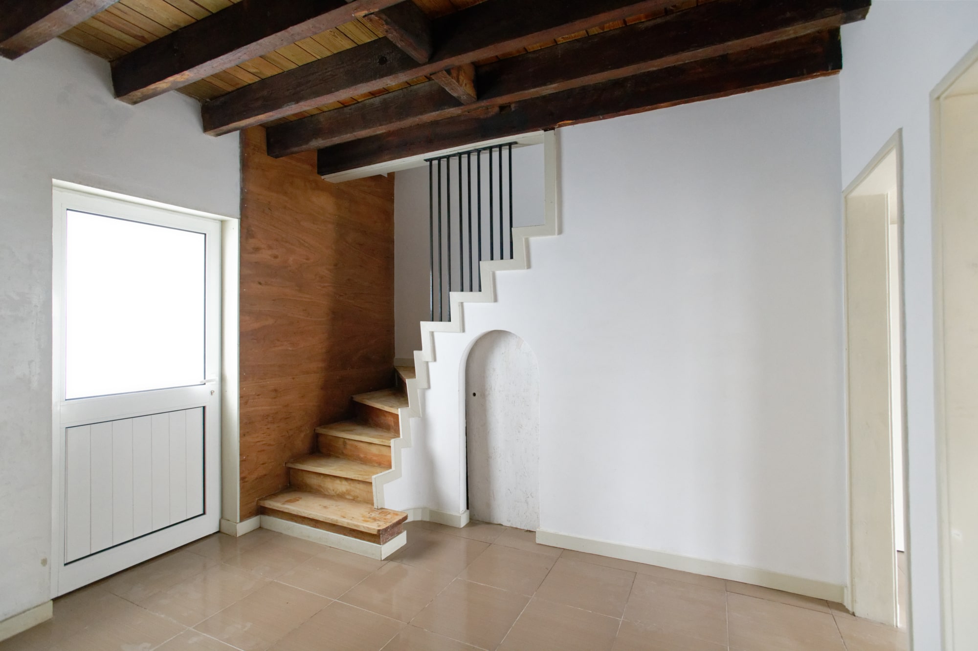 Séjour avec escalier blanc, poutres apparentes et habillage bois