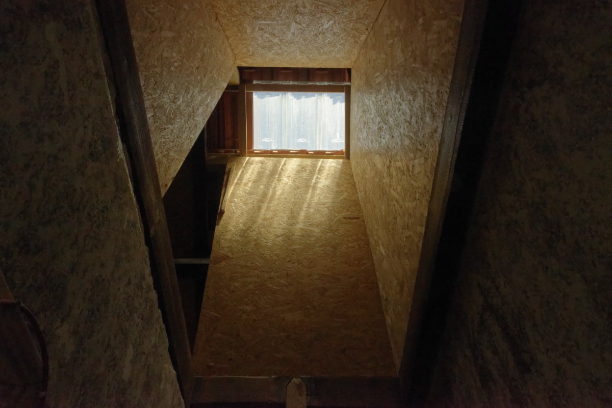 Cage d'escalier habillée de bois avec une petite fenêtre