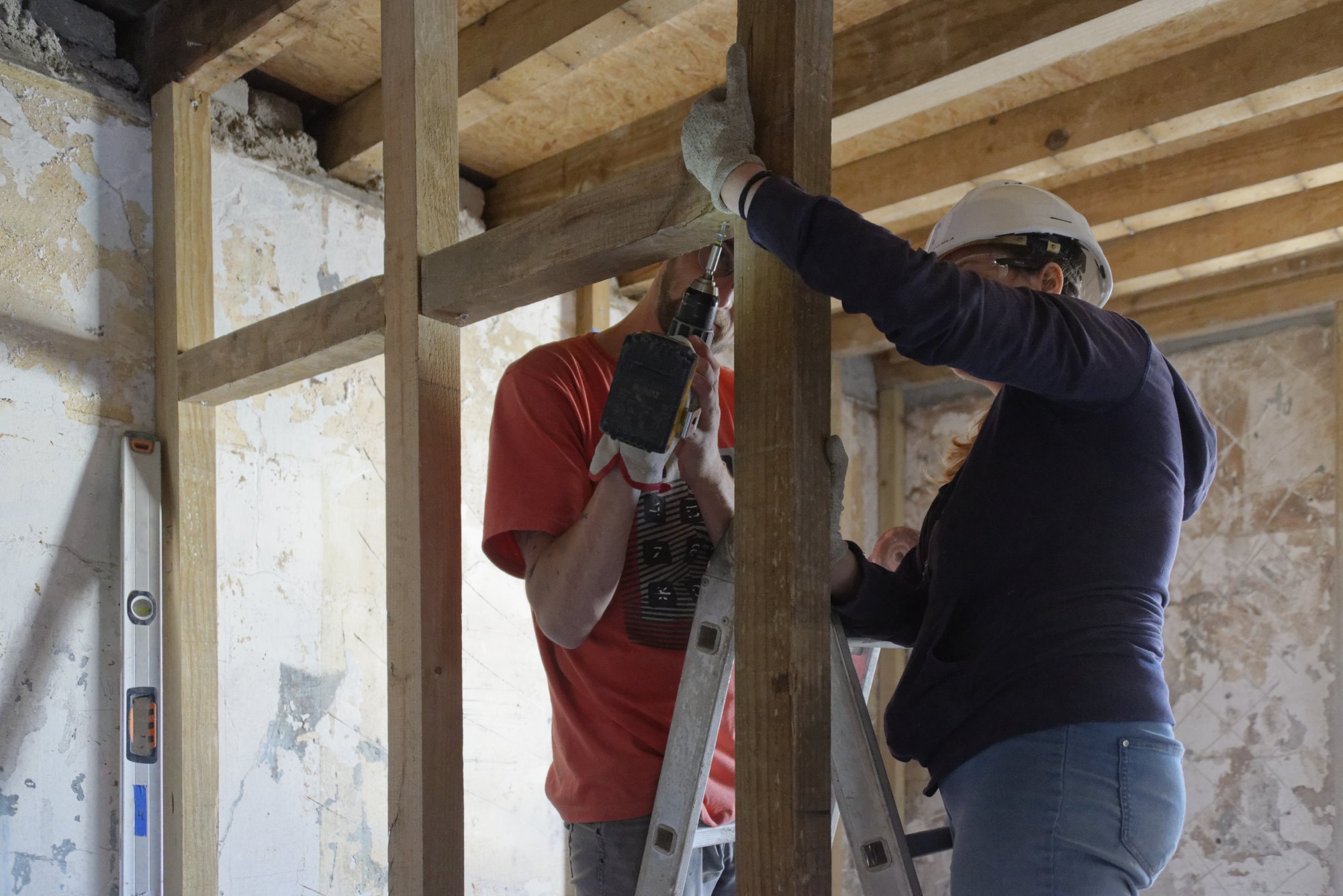Deux participants fixent une ossature bois contre un mur