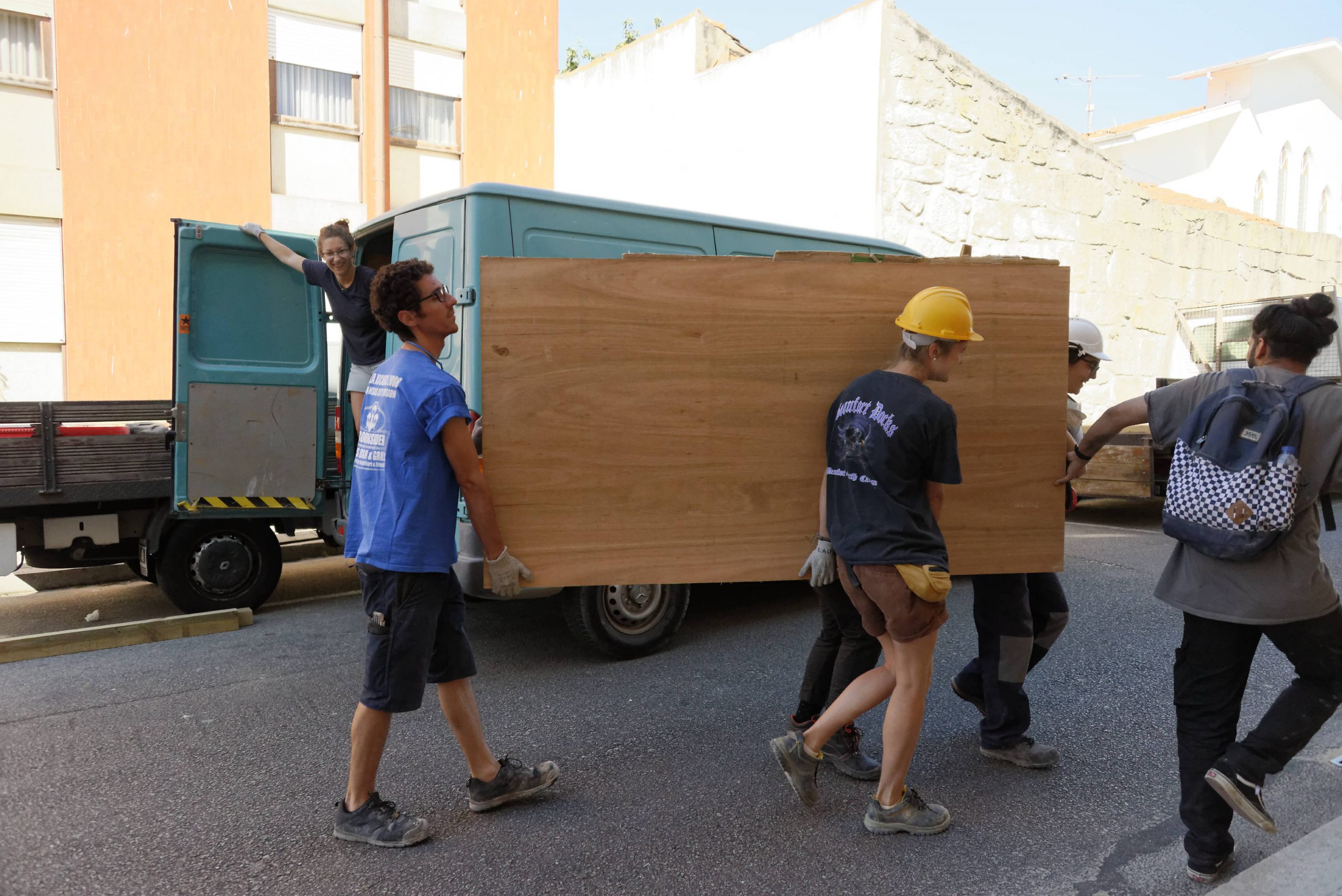 Participants transportant un grand panneau bois dans la rue