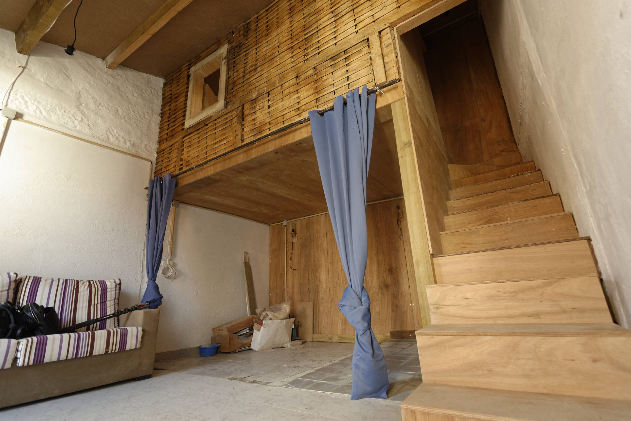 Chambre habillée de bois avec lit en mezzanine et rideau bleu