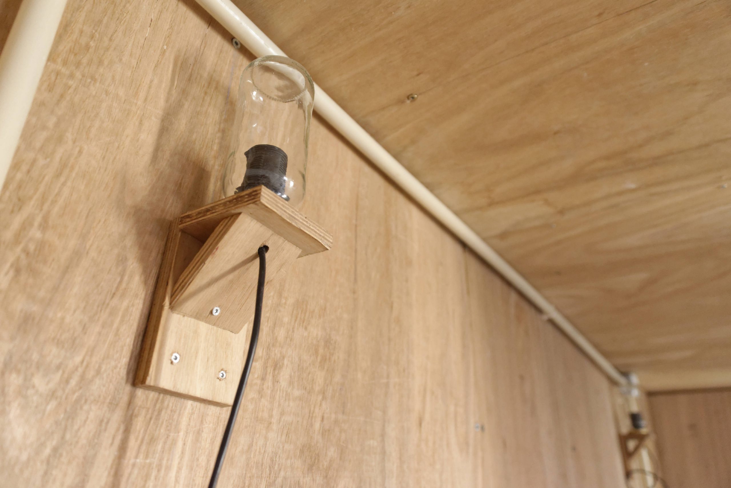 Applique et interrupteur montés sur un panneau de bois, gros plan