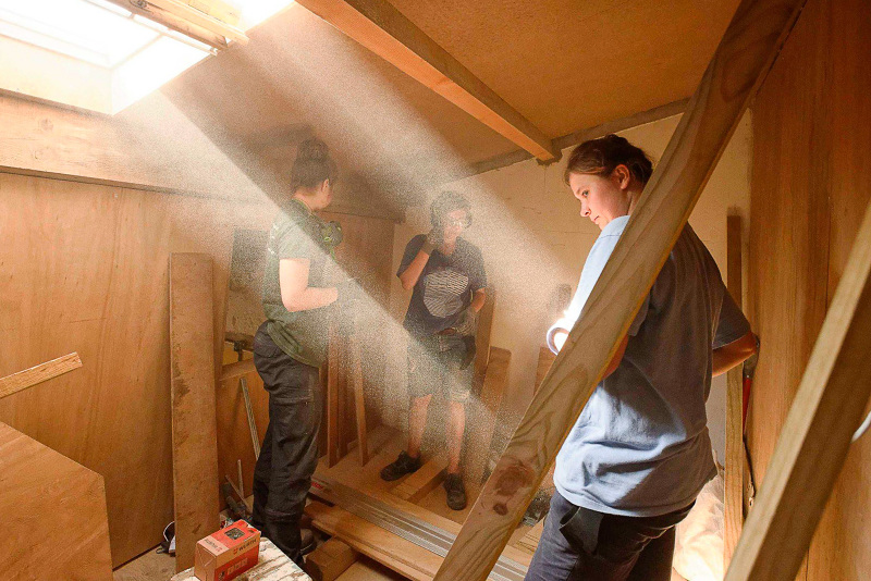 Participants aménageant un escalier en bois, rai de lumière