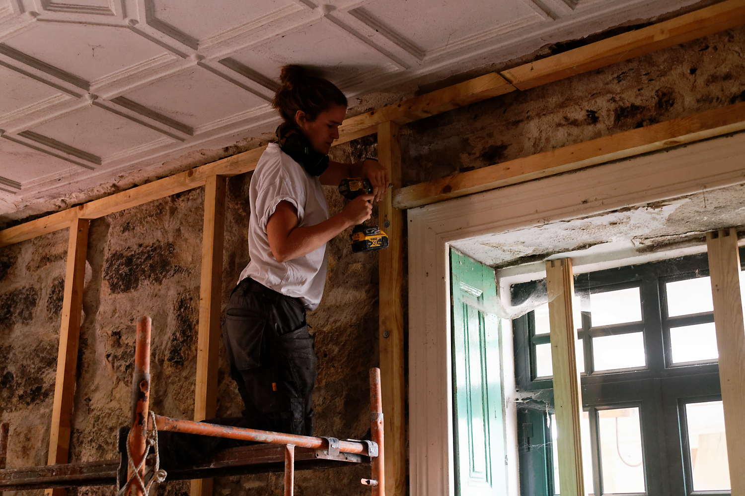 Un participant visse une ossature bois sous un plafond à caissons