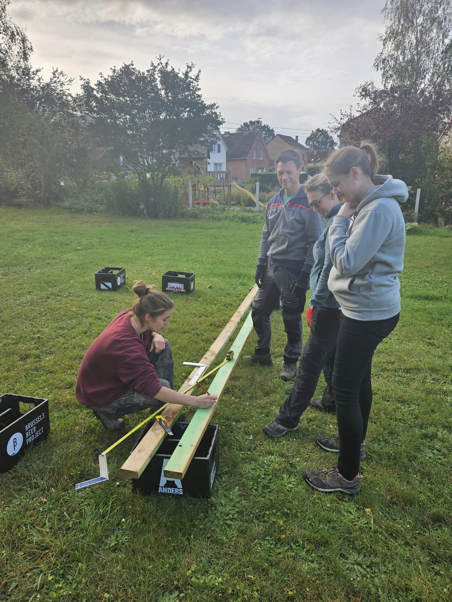 Deux participants assemblent une pièce de bois au sol, en groupe