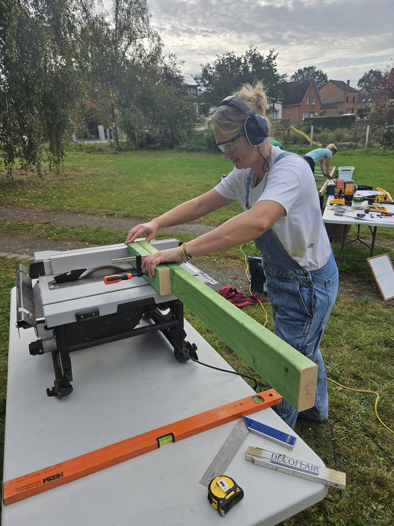 Une participante coupe une planche à la scie sur table