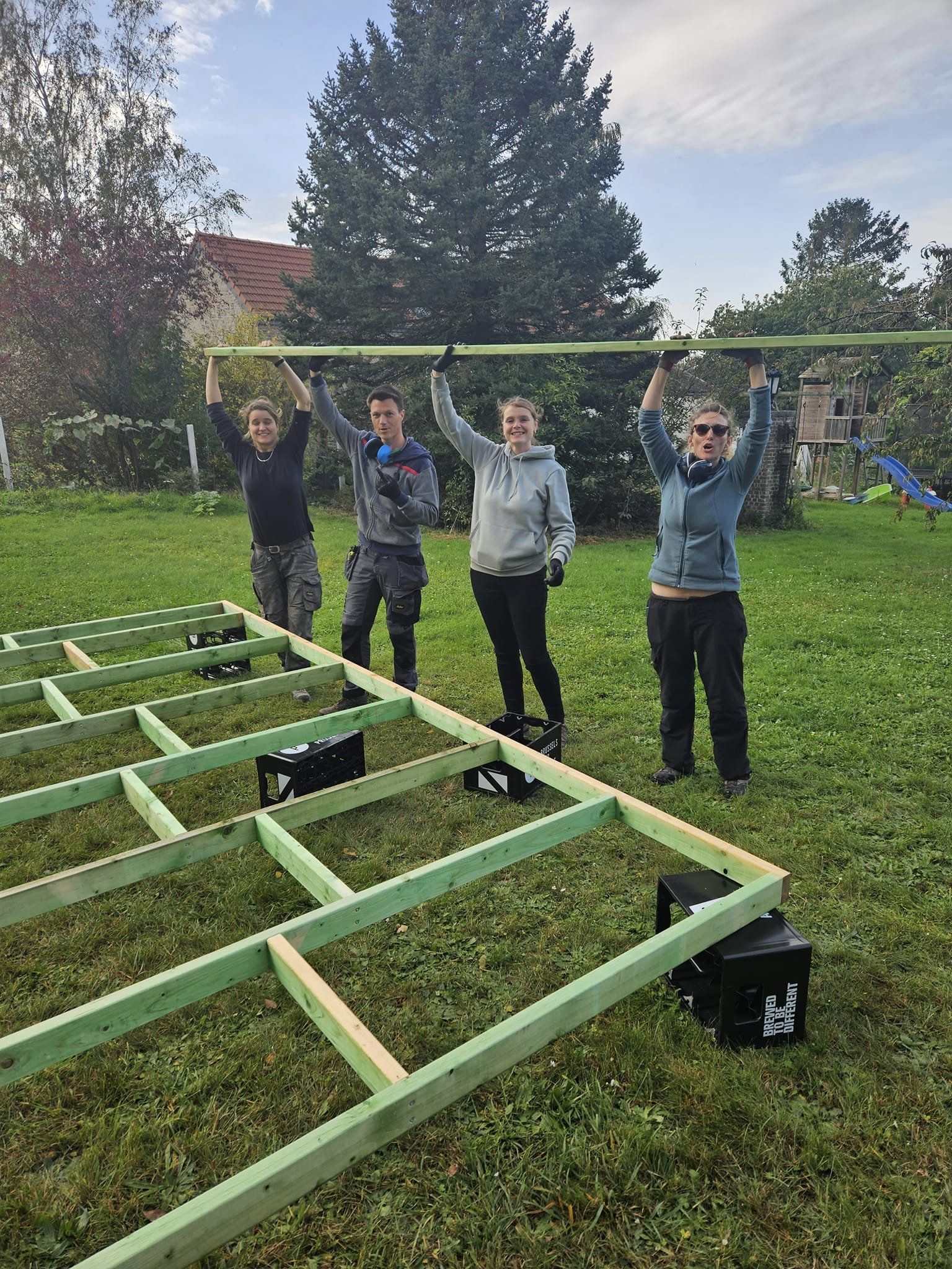 Groupe de participants autour de l'ossature du plancher, bras levés