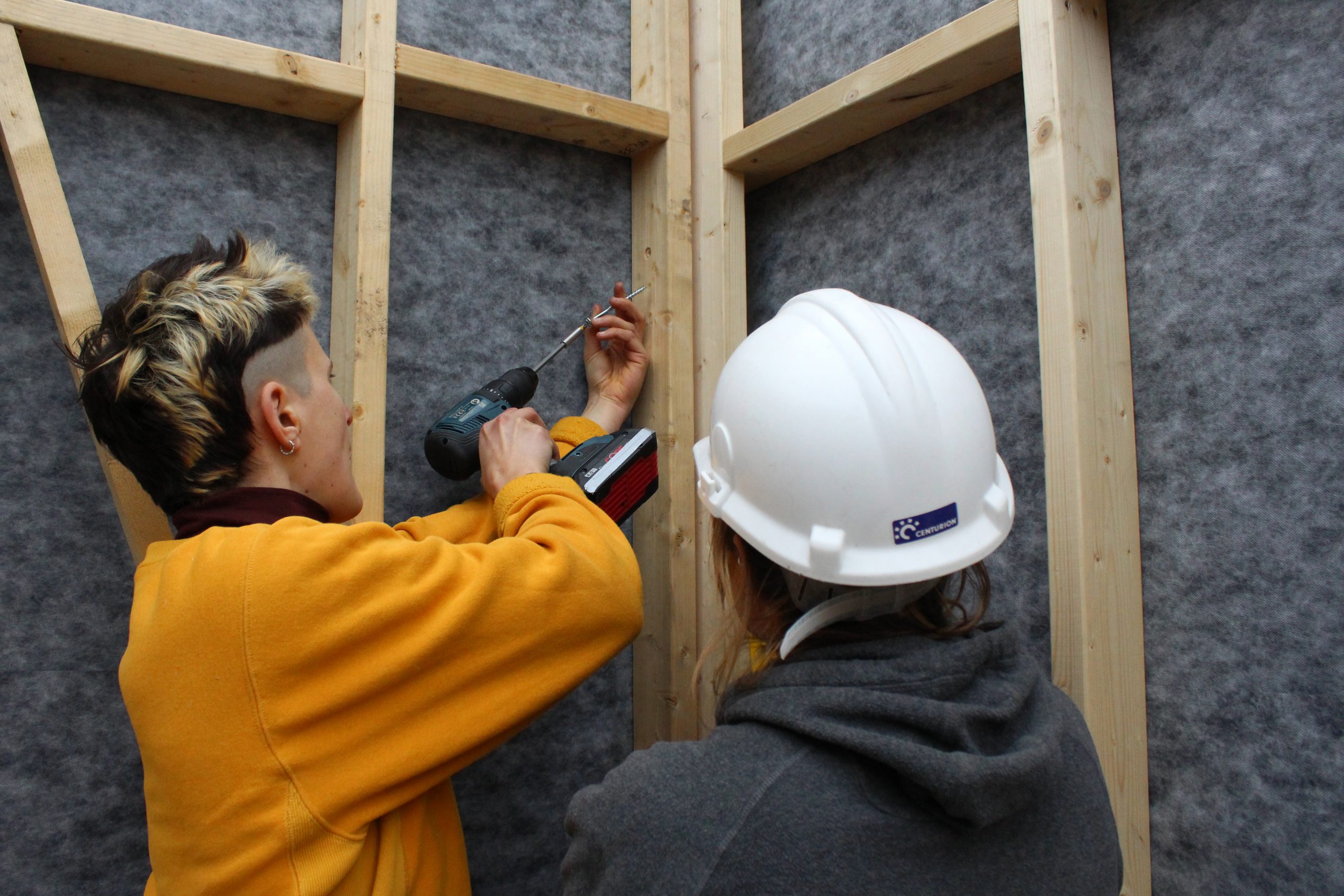 Deux participants vissent l'ossature bois à la perceuse