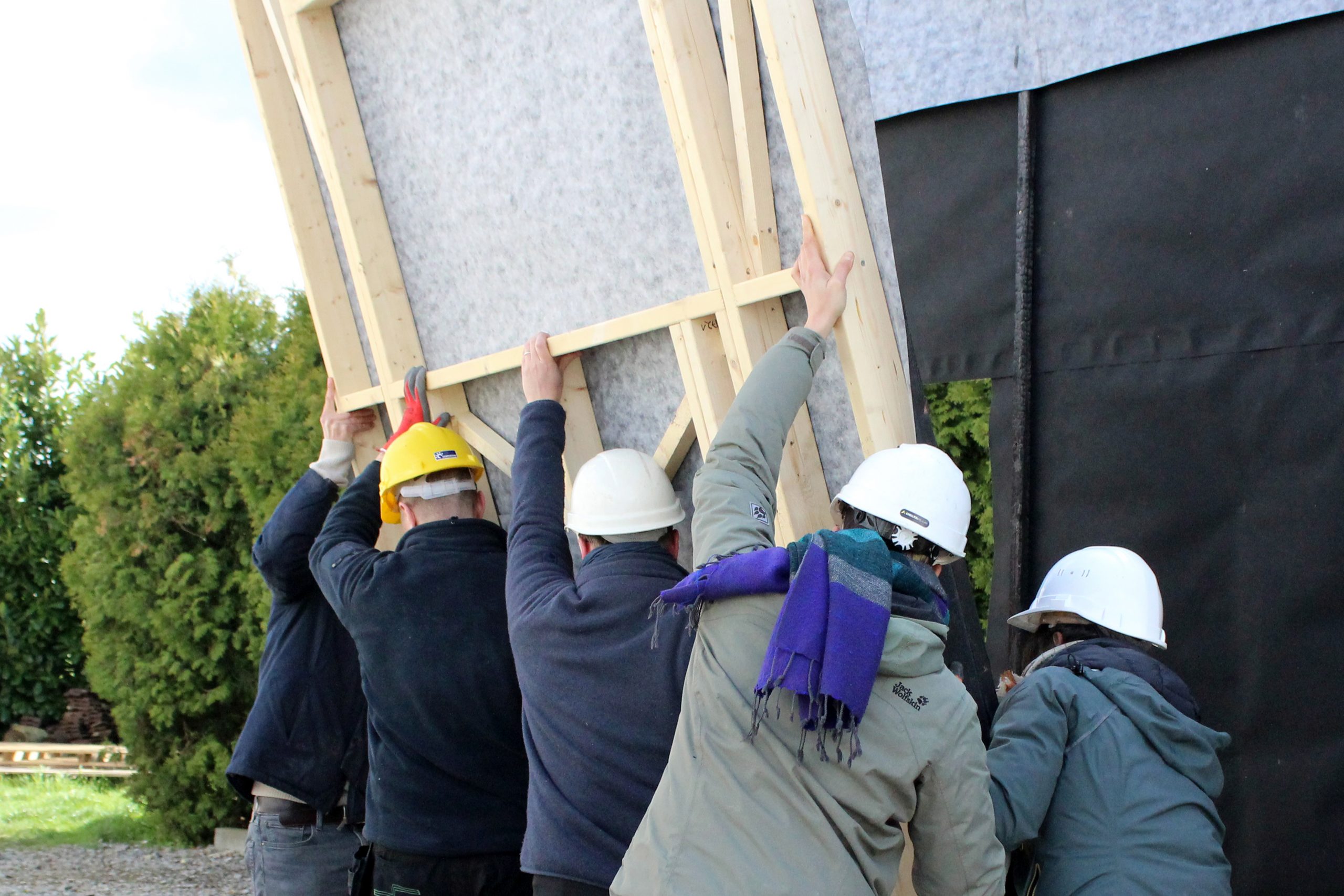 Un groupe redresse un pan de mur habillé de pare-pluie