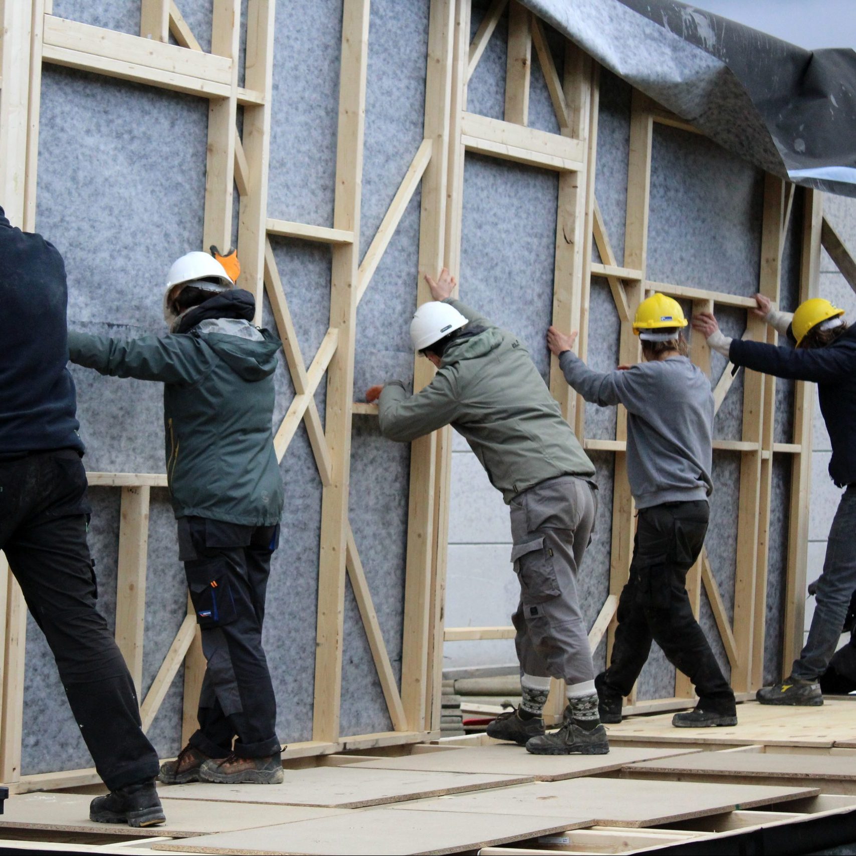 Plusieurs participants ajustent un pan de mur en ossature