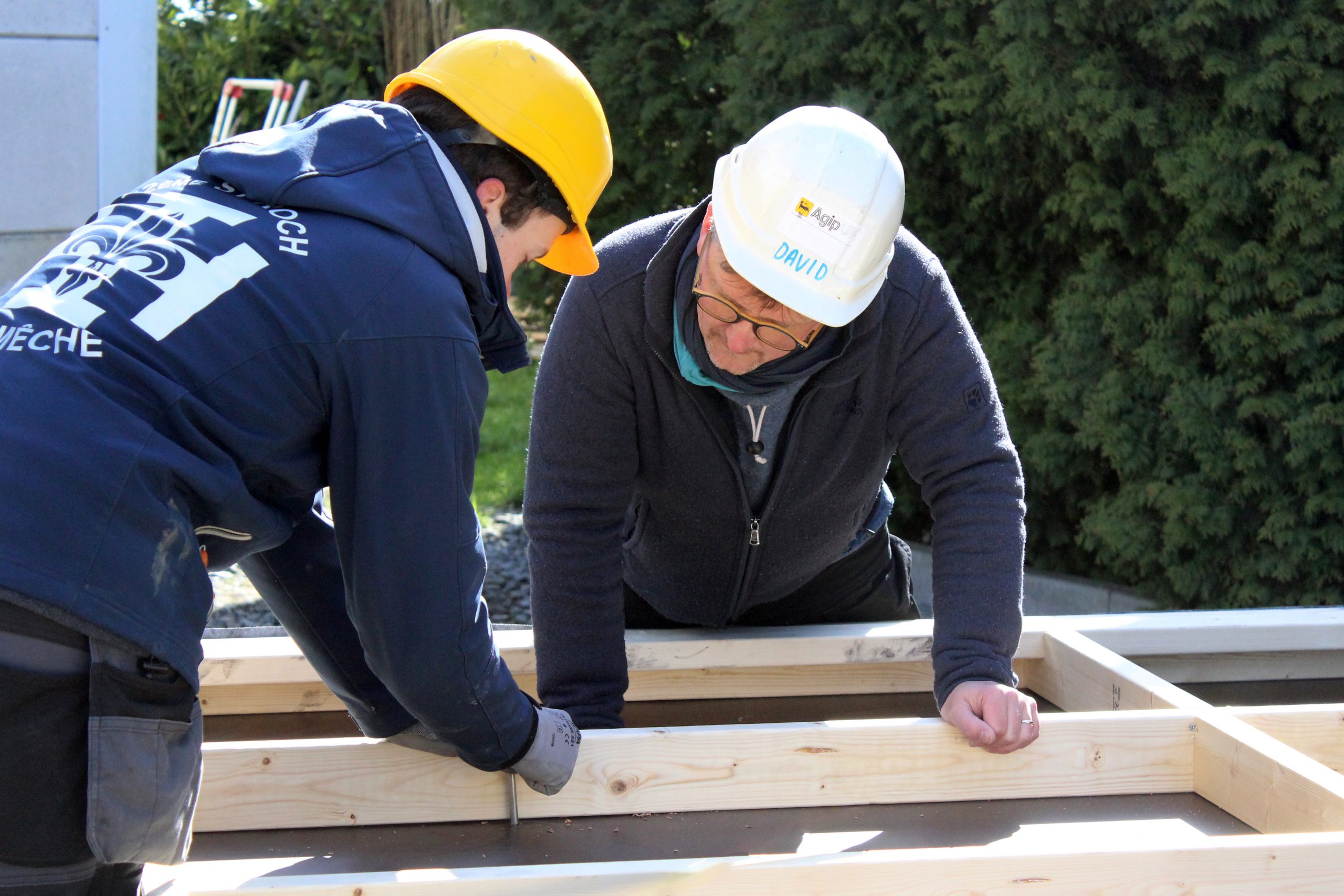 Deux participants agenouillés fixent le plancher-cadre en bois