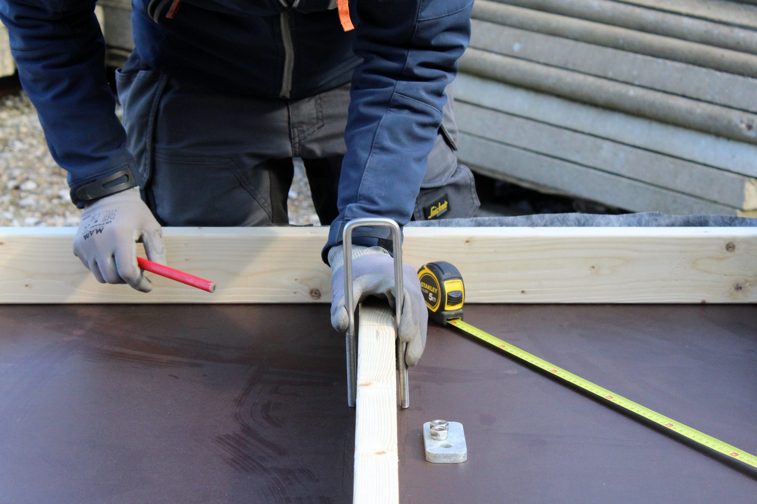 Gros plan sur des mains gantées mesurant un panneau au mètre