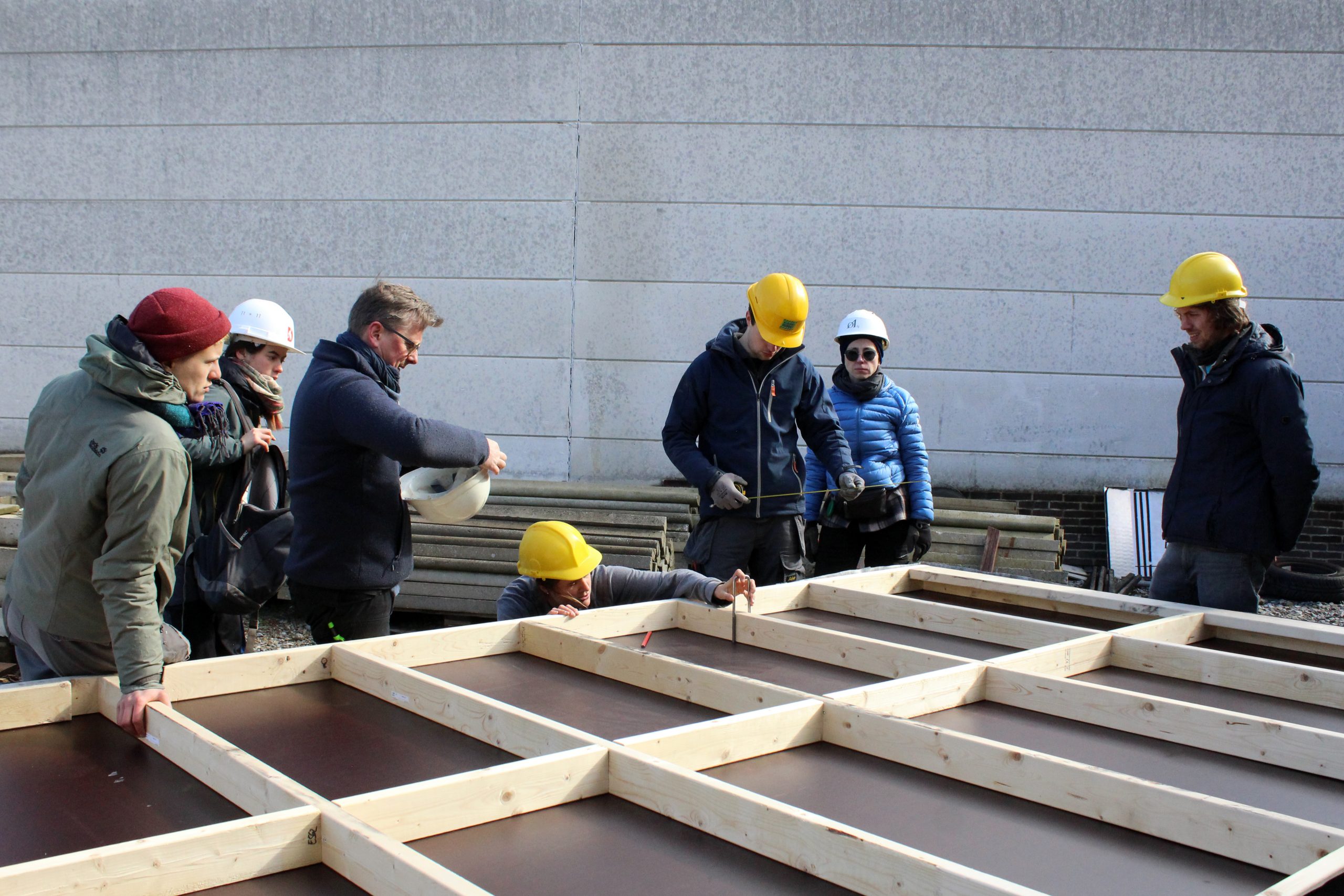 Un groupe assemble le plancher de la tiny house sur le sol pavé