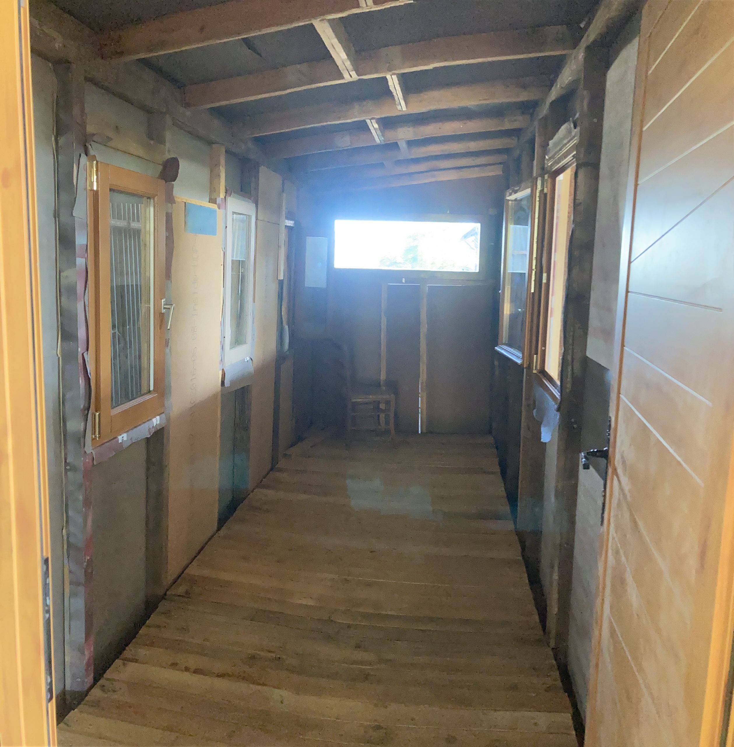Couloir intérieur entièrement lambrissé, la lumière du jour au bout