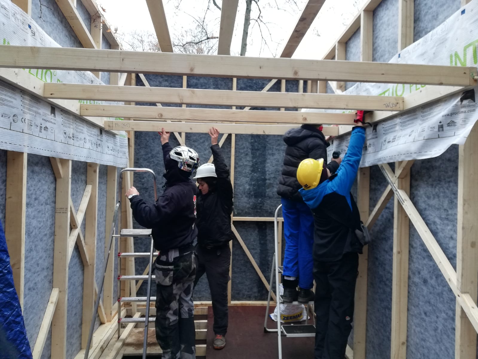Participants montant la charpente de la tiny house sous bâche