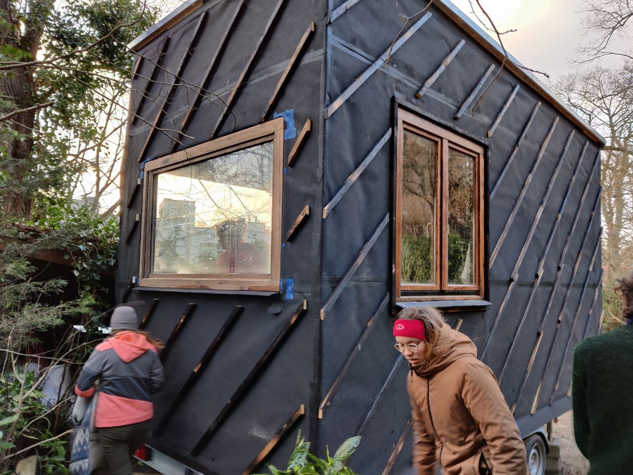 La tiny house au bardage bois brûlé noir, fenêtres posées, dans un jardin
