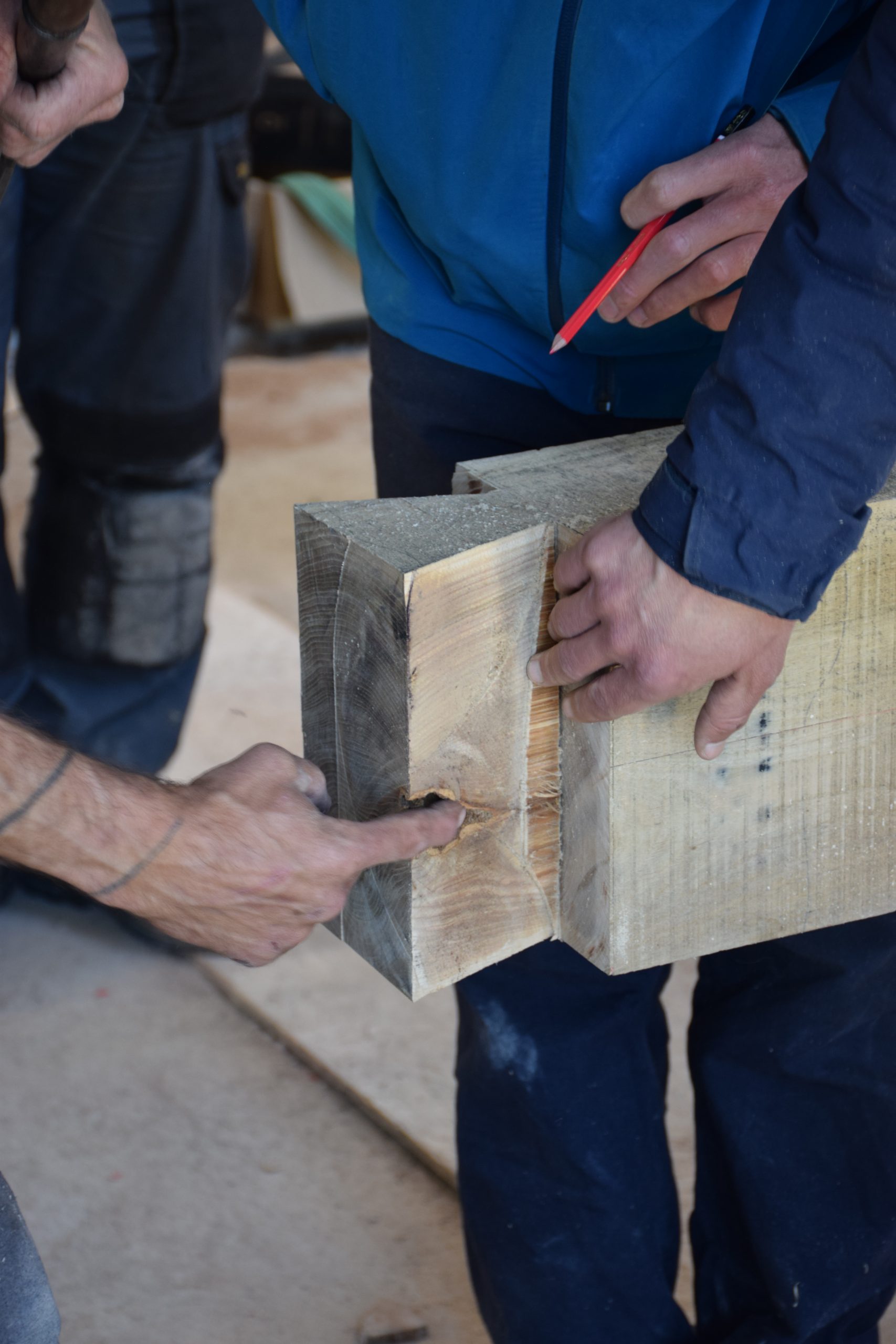 Participants examinant un tenon taillé au bout d'une pièce de bois