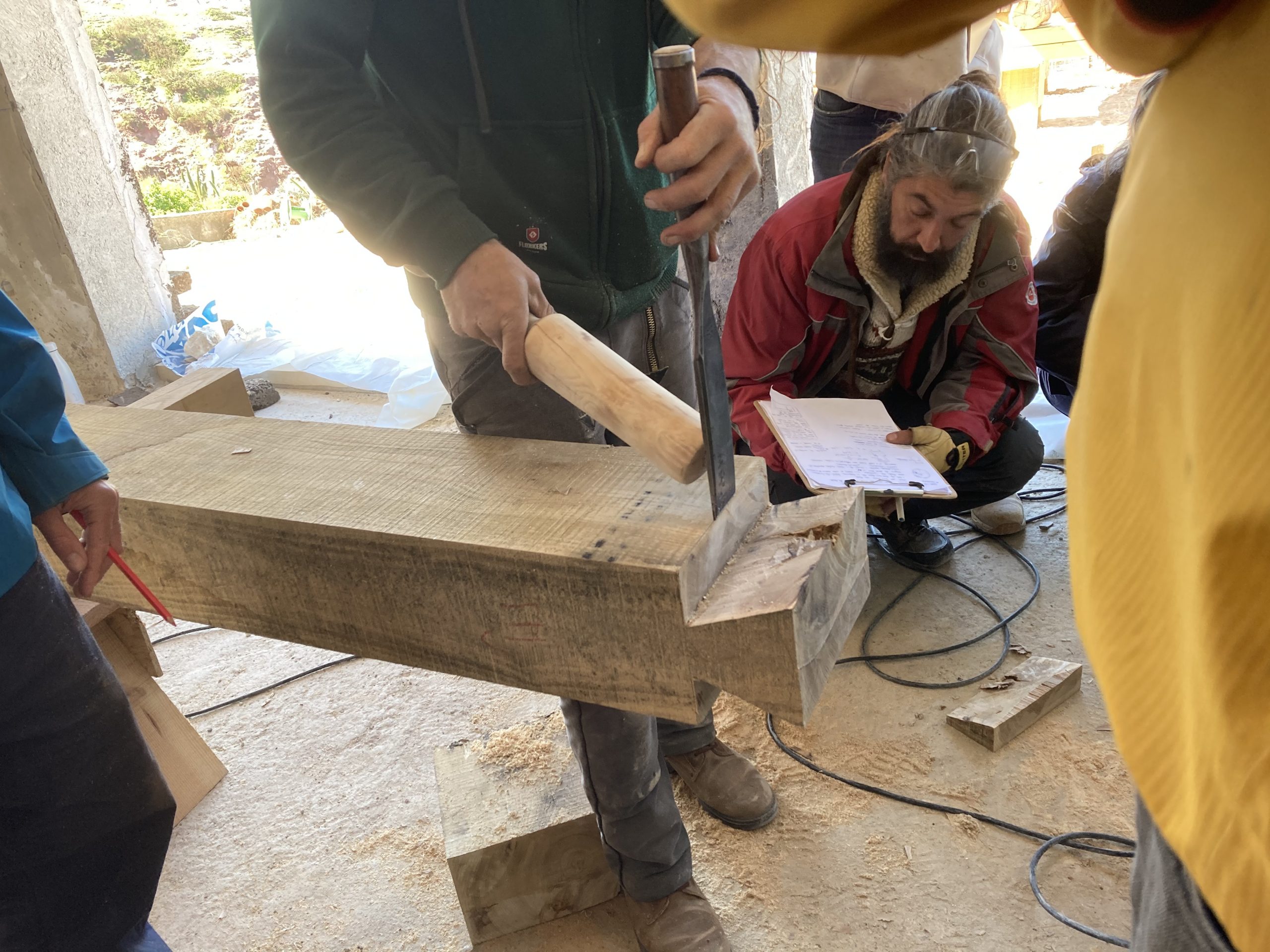 Participants perçant et prenant des notes sur une poutre, face à la mer
