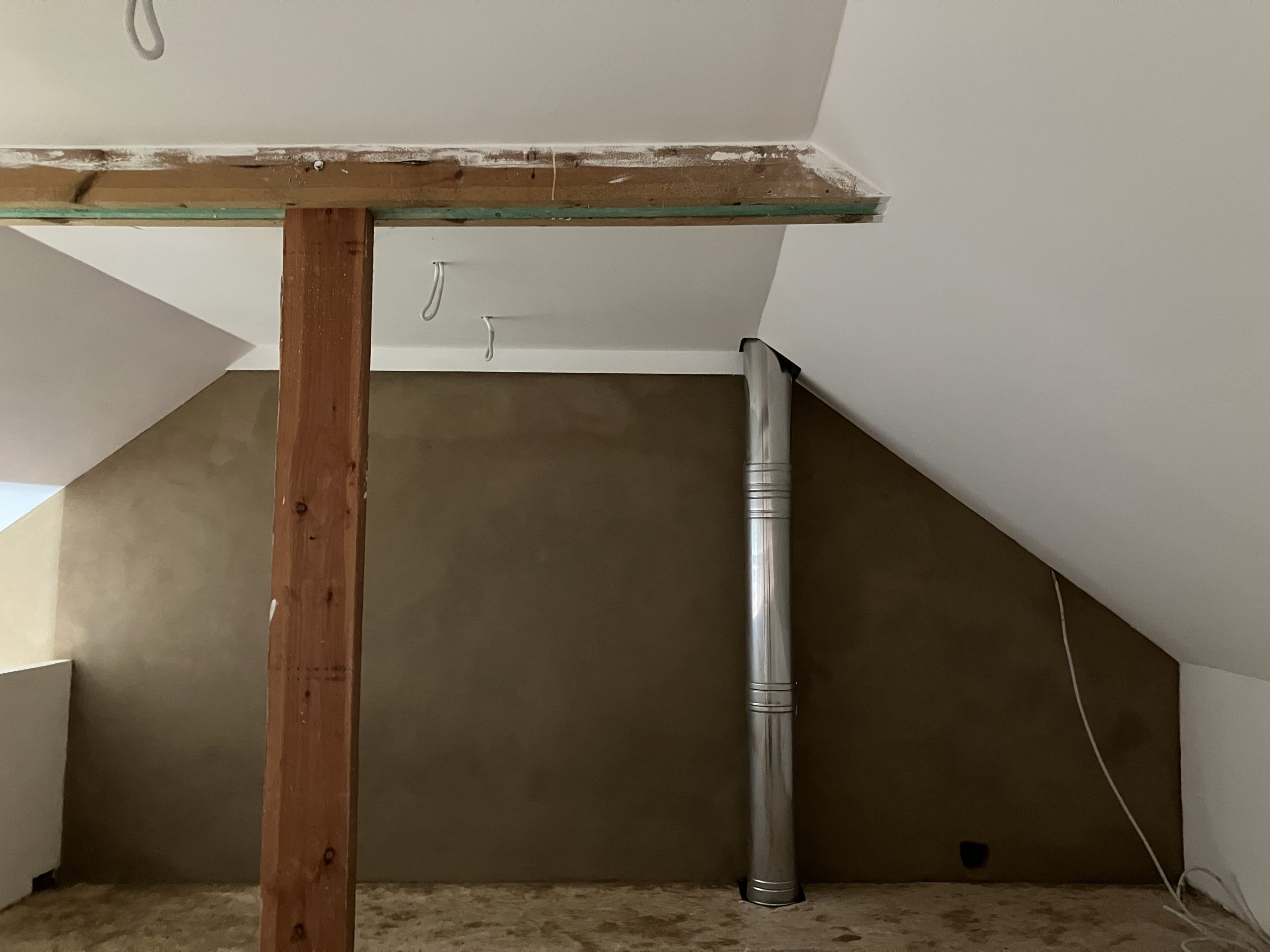 Combles aux rampants enduits en terre crue autour d'un poteau et du conduit